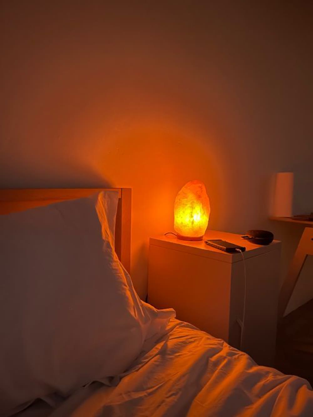 Himalayan salt lamp glowing on a bedside table